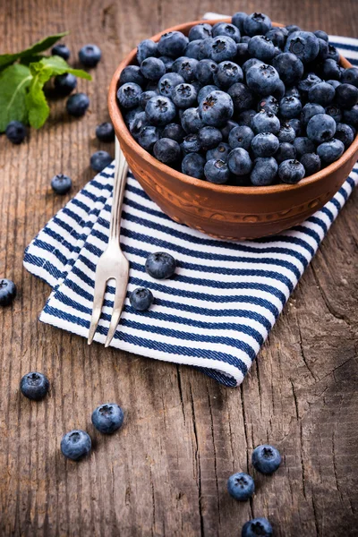 Full bowl of fresh ripe blueberries on old wooden board — Stock Photo, Image