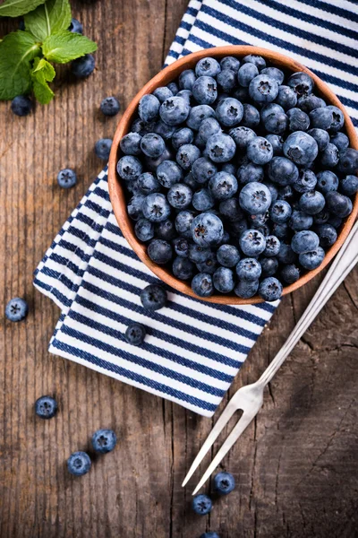 Full bowl of fresh ripe blueberries on old wooden board — Stock Photo, Image