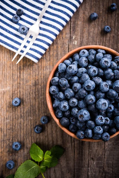 Full bowl of fresh ripe blueberries on old wooden board — Stock Photo, Image