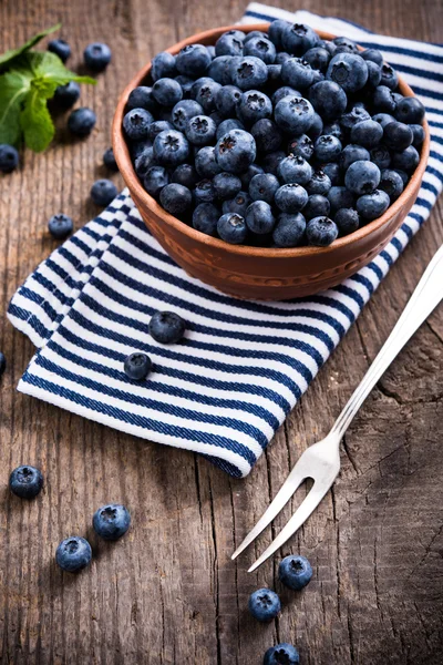 Full bowl of fresh ripe blueberries on old wooden board — Stock Photo, Image