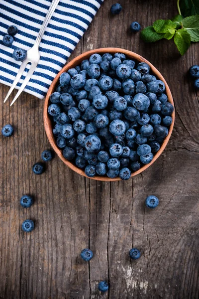 Full bowl of fresh ripe blueberries on old wooden board — Stock Photo, Image