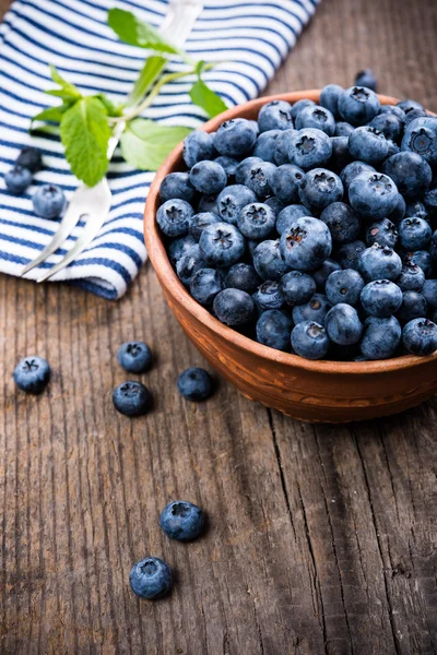 Full bowl of fresh ripe blueberries on old wooden board — Stock Photo, Image