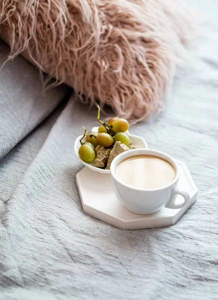 Чашка кави і винограду з затишною подушкою на ковдрі в інтер'єрі домашньої спальні — стокове фото