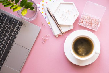 Bayan blogcular iş yerinde, bir fincan kahve ve pembe masa üstünde dizüstü bilgisayar klavyesi