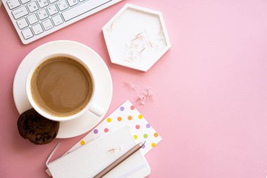 Bayan blogcular iş yerinde, bir fincan kahve ve pembe masa üstünde dizüstü bilgisayar klavyesi