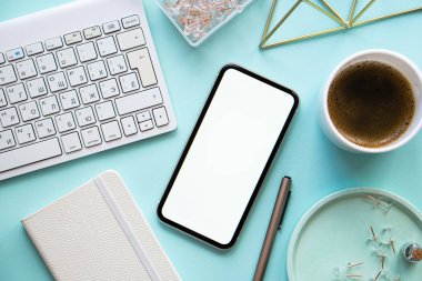 Bayan Freelancers ev pastel mavi işyeri, bir fincan kahve ve akıllı telefon maketi.