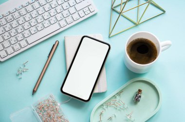 Bayan Freelancers ev pastel mavi işyeri, bir fincan kahve ve akıllı telefon maketi.