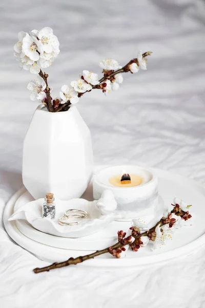 Fleurs branches d'abricot et bougie brûlante sur plateau rond dans la chambre à coucher intérieure, décoration de la maison de printemps blanc — Photo