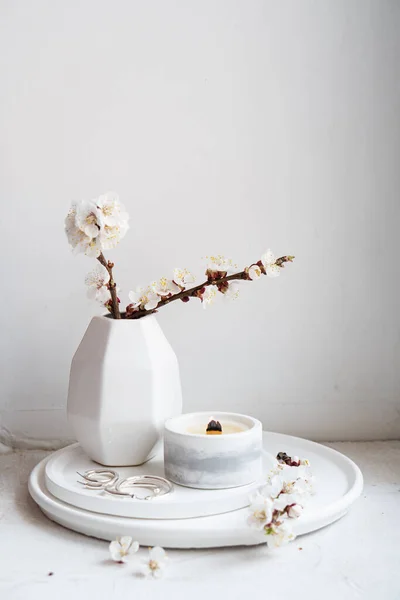 Des branches d'abricot fleuries dans un vase et une bougie allumée sur un plateau rond à l'intérieur de la maison — Photo