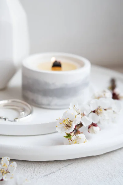 Des branches d'abricot fleuries dans un vase et une bougie allumée sur un plateau rond à l'intérieur de la maison — Photo