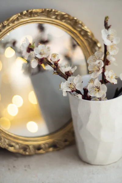 Ramas florecientes de albaricoque en copa y vela encendida frente al espejo —  Fotos de Stock