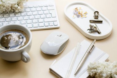 Pc klavyesi, not defteri ve beyaz çiçekli nötr renk masaüstü, ofis nesneleri