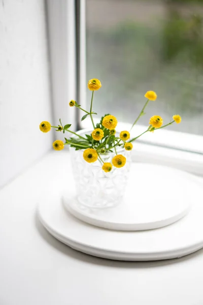 Sarı çiçekli beyaz ev dekorasyonu, seramik vazo ve tepside cam. — Stok fotoğraf