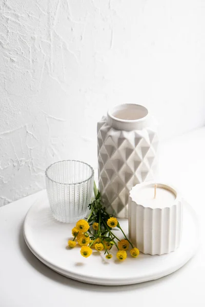 Decoración casera blanca con flores amarillas, jarrón de cerámica, vela y vidrio en bandeja —  Fotos de Stock