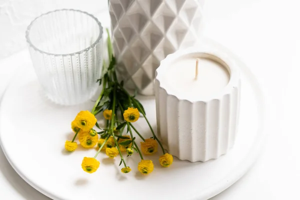 Décoration de maison blanche avec des fleurs jaunes, vase en céramique, bougie et verre sur plateau — Photo