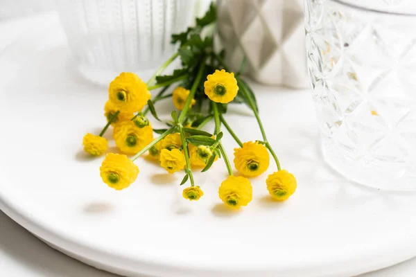 Decoración blanca para el hogar con flores amarillas, jarrón de cerámica y vidrio en bandeja —  Fotos de Stock