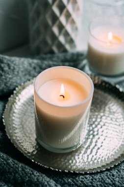 Cam şamdanda yanan beyaz mum, eski metal tepside, sıcak sıcak bir ev.