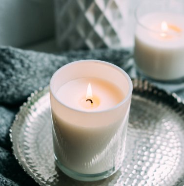 Cam şamdanda yanan beyaz mum, eski metal tepside, sıcak sıcak bir ev.