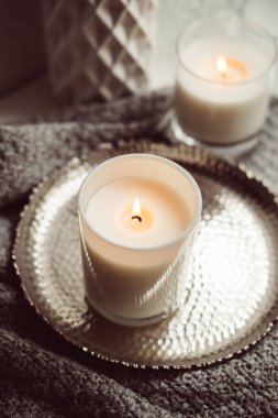 Cam şamdanda yanan beyaz mum, eski metal tepside, sıcak sıcak bir ev.