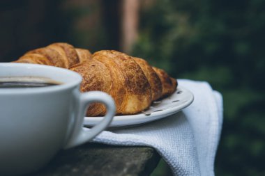 Eski ahşap masada kahve ve kruvasan.