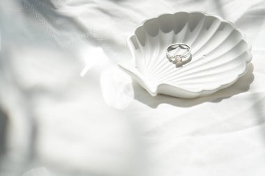 Nişan yüzüğü desenli keten arka planda kabuk şeklinde mücevher plakası.