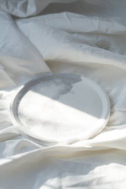 Beyaz desenli keten zemin üzerine boş yuvarlak tepsi, tasarımcı mücevher tabağı