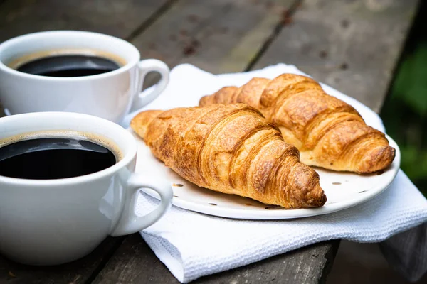 Coffee and croissants on old rustic wooden table — Stock Photo, Image