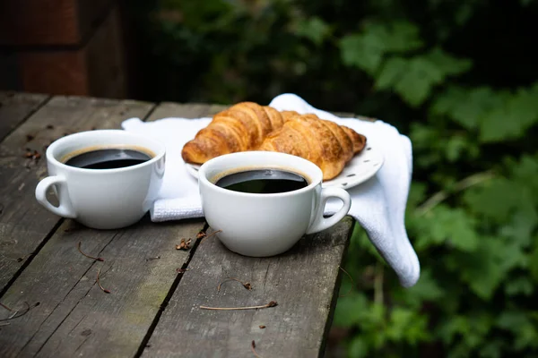 Kaffe och croissanter på gammalt rustikt träbord — Stockfoto
