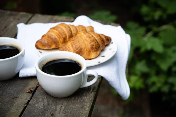 Kaffee und Croissants auf altem rustikalen Holztisch — Stockfoto