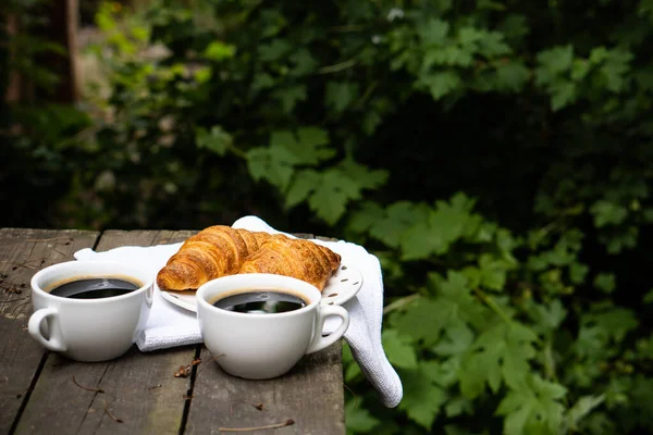 Koffie en croissants op oude rustieke houten tafel — Stockfoto
