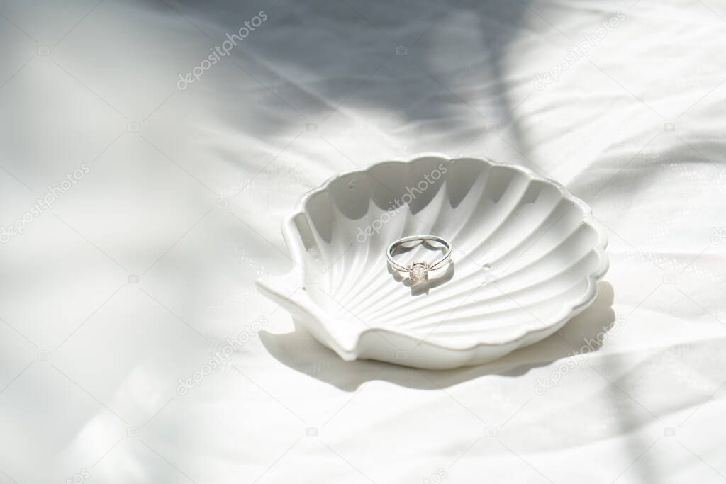 Engagement ring in shell-shaped jewelry plate on textured linen background