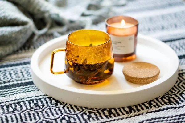 Tasse Tee und gemütliche brennende Kerze auf weißem Tablett — Stockfoto