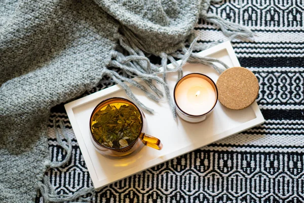 Taza de té y acogedora vela ardiente en bandeja blanca — Foto de Stock