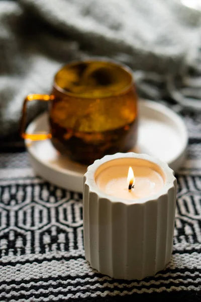 Taza transparente amarilla de té de hierbas y acogedora vela ardiente en bandeja blanca — Foto de Stock