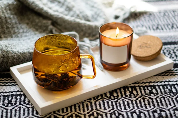 Taza amarilla transparente de té de hierbas y acogedora vela ardiente con etiqueta engomada maqueta — Foto de Stock