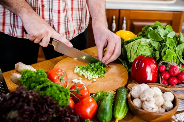 Man cuts fresh spring vegetables — Stock Photo, Image