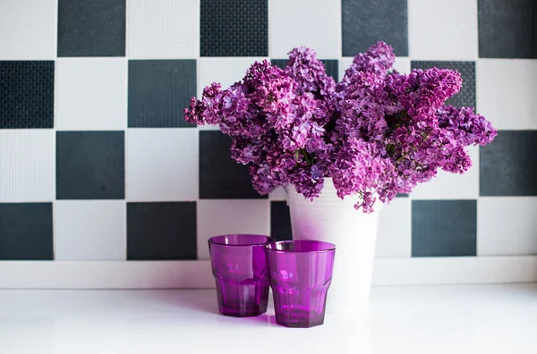 Lilacs in a vase and glasses — Stock Photo, Image