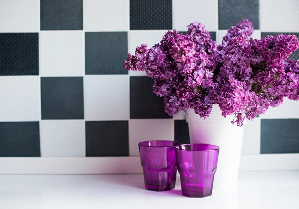 Lilacs in a vase and glasses — Stock Photo, Image