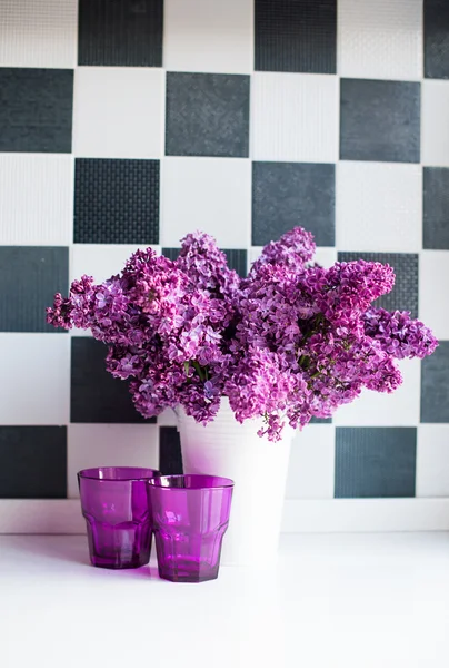 Flieder in Vase und Gläsern — Stockfoto