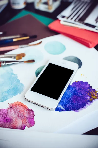 Smartphone na stole v ateliéru umělce — Stock fotografie