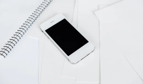 Смартфон и чистая белая бумага — стоковое фото