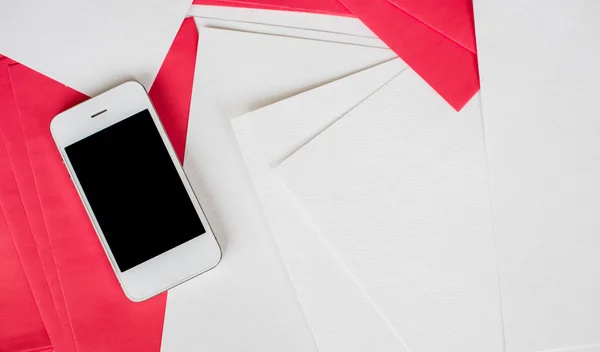 Smartphone com folhas de papel branco e vermelho — Fotografia de Stock