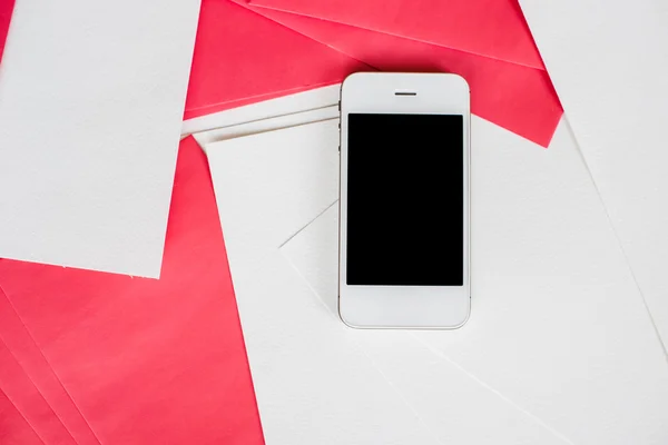 Smartphone avec feuilles de papier blanc et rouge — Photo