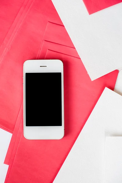 Smartphone avec feuilles de papier blanc et rouge — Photo