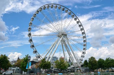 Kanada, Montreal - 11 Temmuz 2021: Montreal 'in Eski Limanı' ndaki La Grande Roue de Montreal dönme dolabının mavi gökyüzü ve bulutların üzerindeki manzarası. Montreal 'in eski limanı Quebec' in tarihi limanıdır..