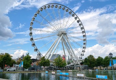 Kanada, Montreal - 11 Temmuz 2021: Montreal 'in Eski Limanı' ndaki La Grande Roue de Montreal dönme dolabının mavi gökyüzü ve bulutların üzerindeki manzarası. Montreal 'in eski limanı Quebec' in tarihi limanıdır..