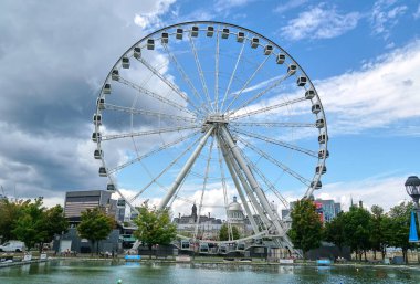 Kanada, Montreal - 11 Temmuz 2021: Montreal 'in Eski Limanı' ndaki La Grande Roue de Montreal dönme dolabının mavi gökyüzü ve bulutların üzerindeki manzarası. Montreal 'in eski limanı Quebec' in tarihi limanıdır..