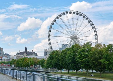 Kanada, Montreal - 11 Temmuz 2021: Montreal 'in Eski Limanı' ndaki La Grande Roue de Montreal dönme dolabının mavi gökyüzü ve bulutların üzerindeki manzarası. Montreal 'in eski limanı Quebec' in tarihi limanıdır..
