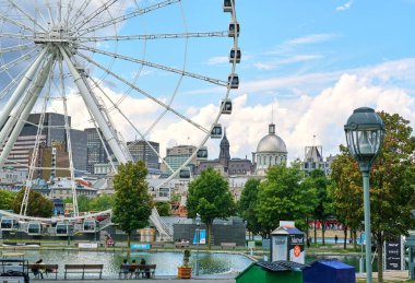 Kanada, Montreal - 11 Temmuz 2021: Montreal Eski Limanı manzarası. Dönme dolap La Grande Roue, Bonsecours Pazarı, belediye binaları mavi gökyüzü ve bulutlar üzerinde.