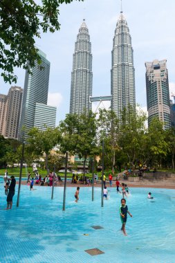 Children at a pool in Kuala Lumpur swimming in the cool water wi